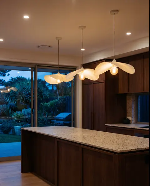 Warm pendant lights glowing over a timber kitchen island at dusk